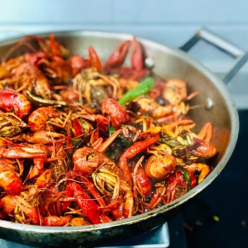 A sizzling pan filled with succulent crawfish and vibrant spices, showcasing a seafood feast.